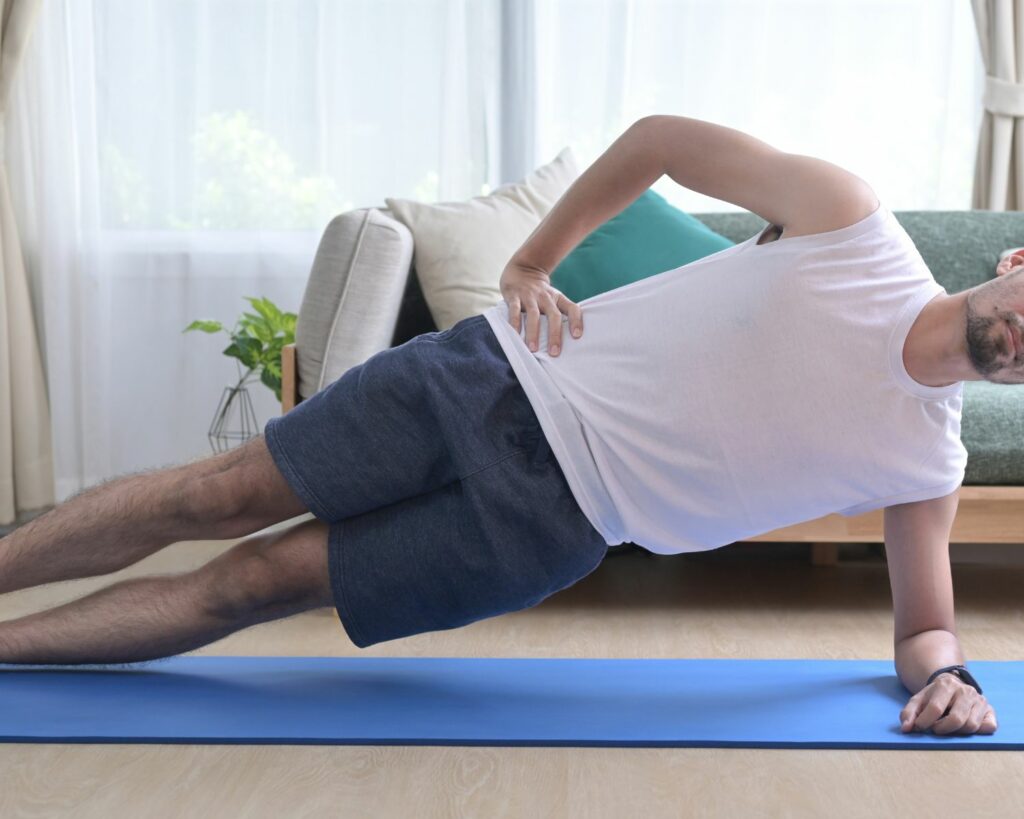 Jeune homme faisant du gainage sur un tapis chez lui