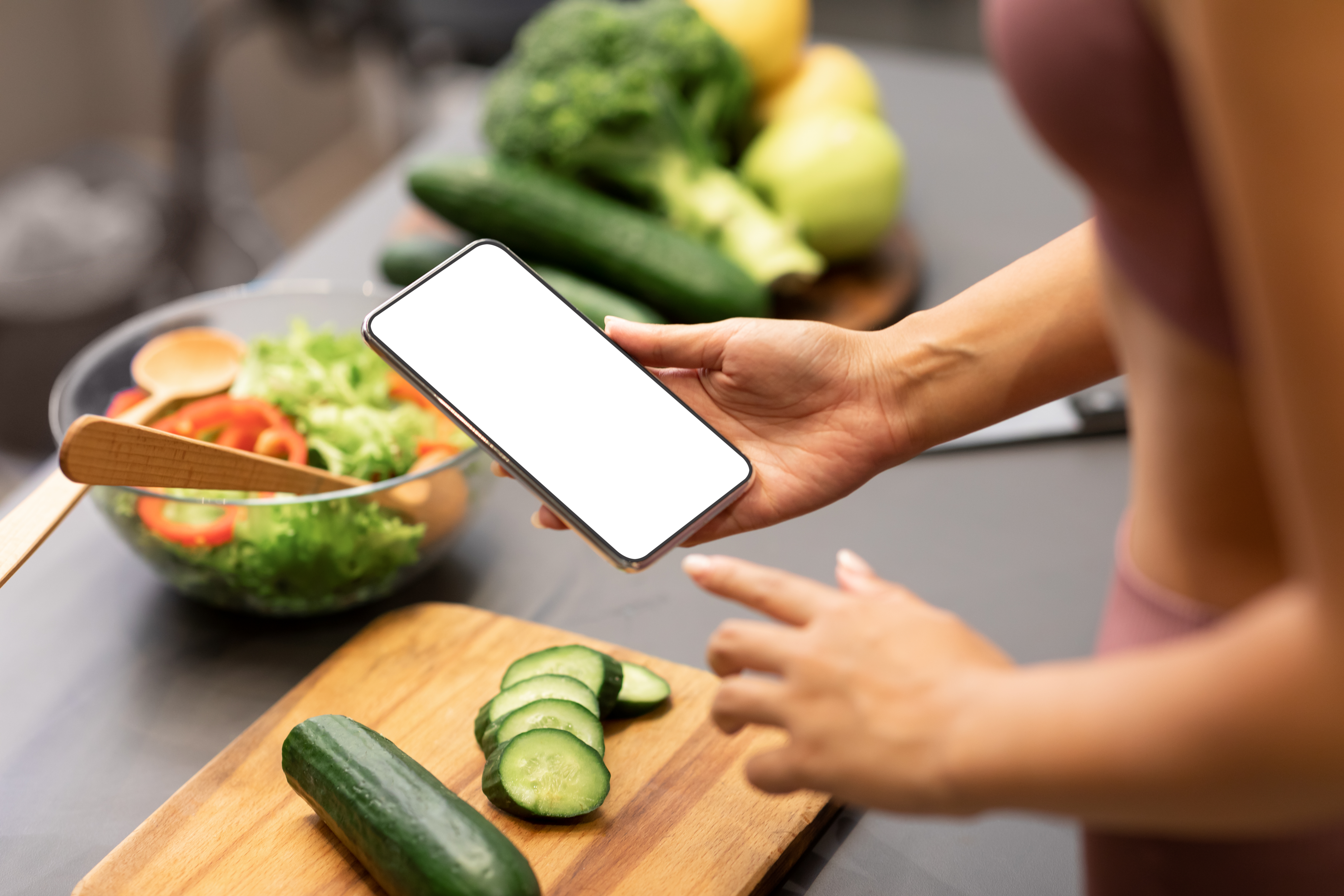 Woman Using Smartphone Cooking Healthy Dinner For Weight-Loss In Kitchen