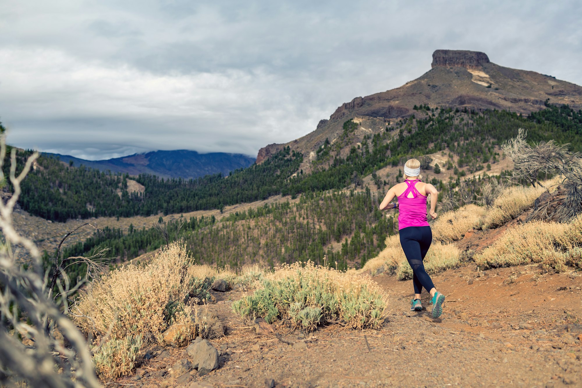 Trail running girl in mountains on rocky footpath