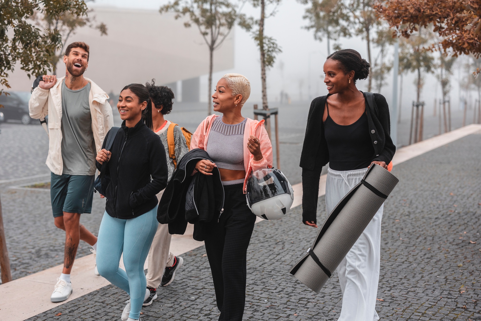 Athletes walking in the city after training carrying sports equipment