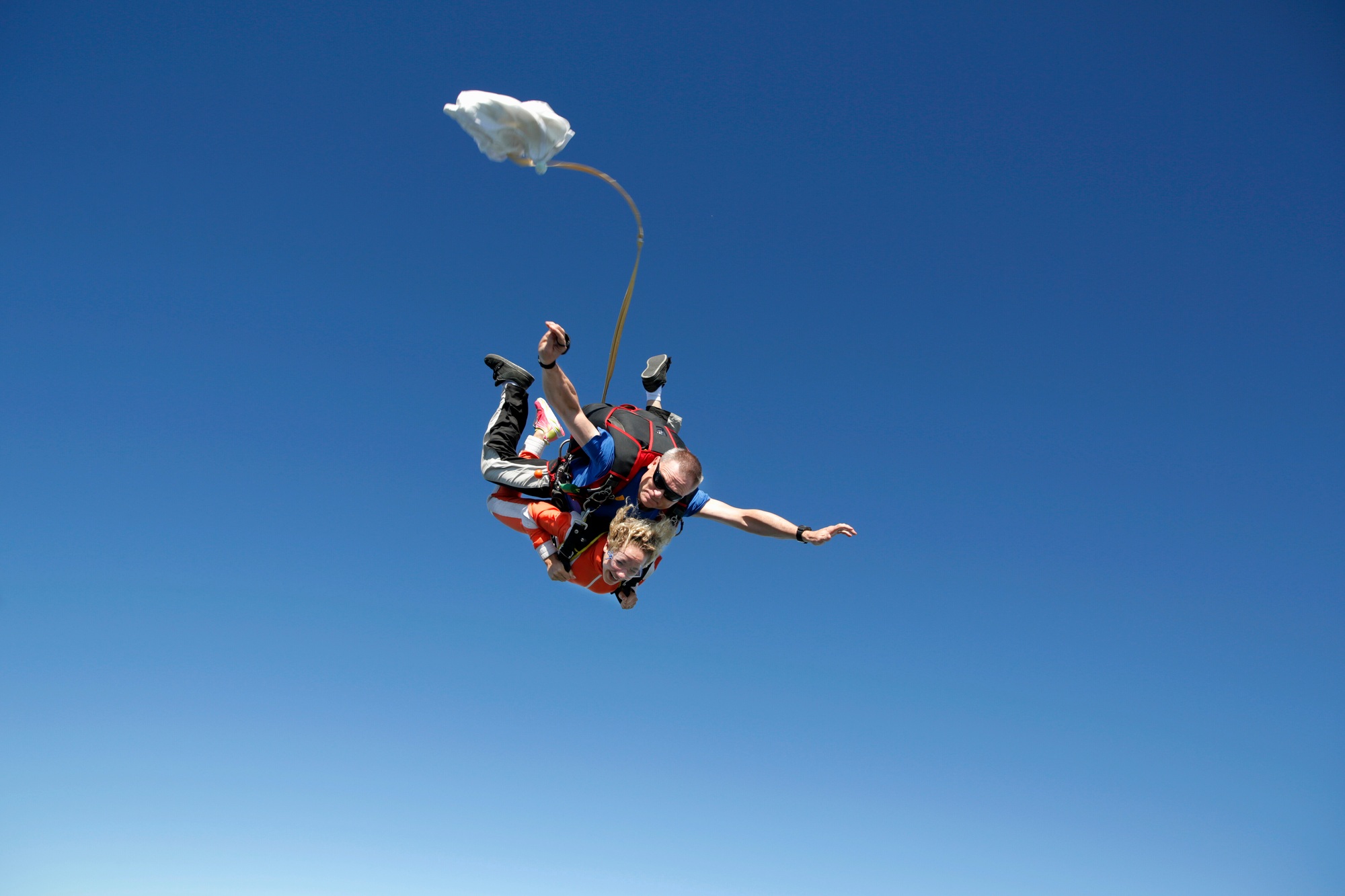 Tandem sky divers free falling with parachute opening, Interlaken, Berne, Switzerland